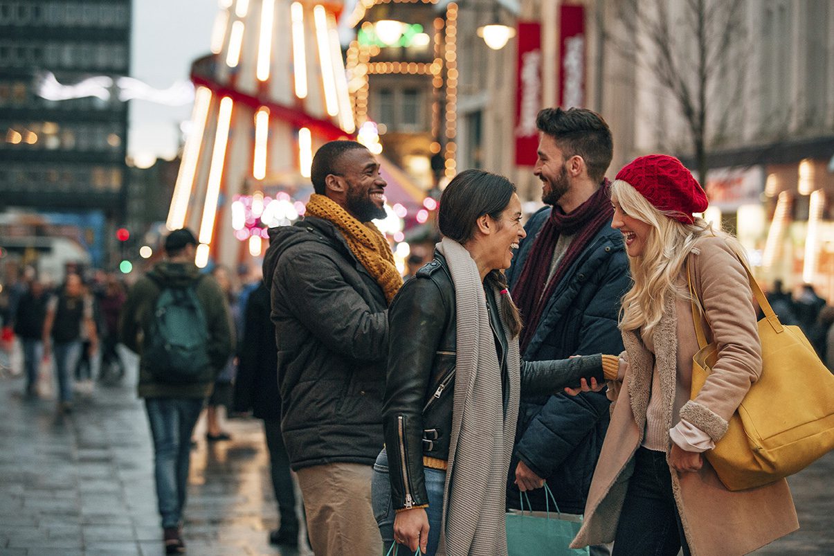 Two couples meeting on the street to do some holiday shopping